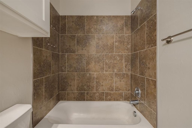 bathroom featuring tiled shower / bath combo and toilet