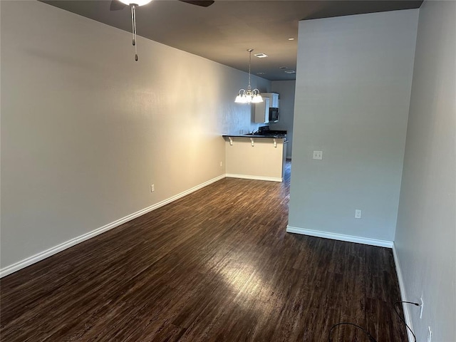 1017 SW 91st St, Oklahoma City, OK 73139 - spare room featuring ceiling fan, dark wood finished floors, a chandelier, and baseboards