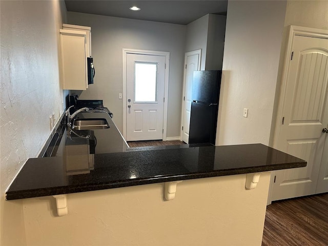 1017 SW 91st St, Oklahoma City, OK 73139 - kitchen with appliances with stainless steel finishes, white cabinets, a breakfast bar, a peninsula, and dark wood finished floors