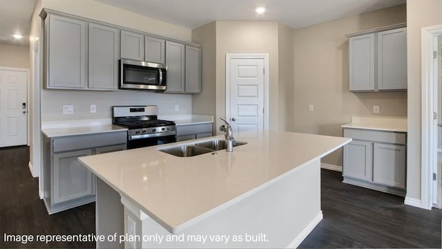 kitchen featuring gray cabinets, light countertops, appliances with stainless steel finishes, a sink, and an island with sink