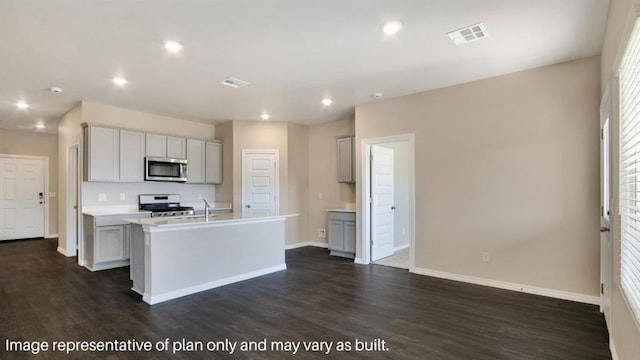 kitchen with visible vents, a kitchen island with sink, stainless steel appliances, light countertops, and gray cabinetry