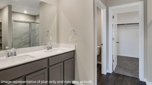 bathroom featuring toilet, a stall shower, a spacious closet, and a sink