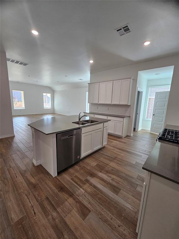 kitchen with dishwasher, a center island with sink, sink, dark hardwood / wood-style floors, and white cabinetry