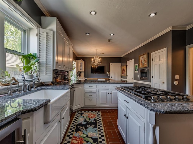 kitchen with pendant lighting, stainless steel gas stovetop, white cabinets, kitchen peninsula, and a chandelier