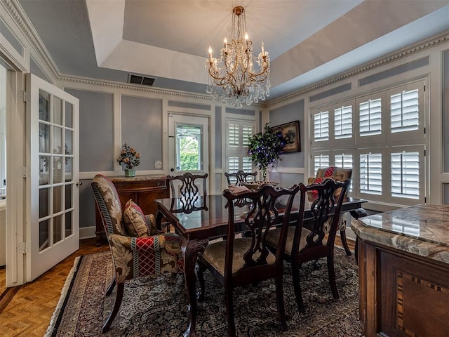 dining area with a tray ceiling, parquet floors, and a notable chandelier