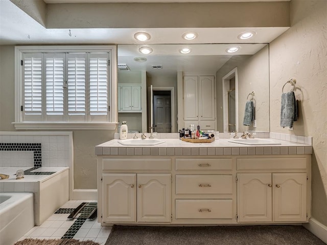 bathroom featuring decorative backsplash, vanity, tile patterned flooring, and a tub to relax in