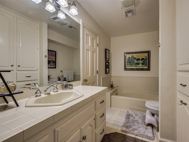 bathroom featuring tile patterned flooring, vanity, a tub to relax in, and toilet