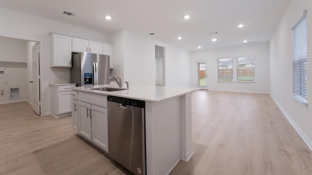 kitchen with a center island with sink, stainless steel appliances, light countertops, white cabinets, and a sink