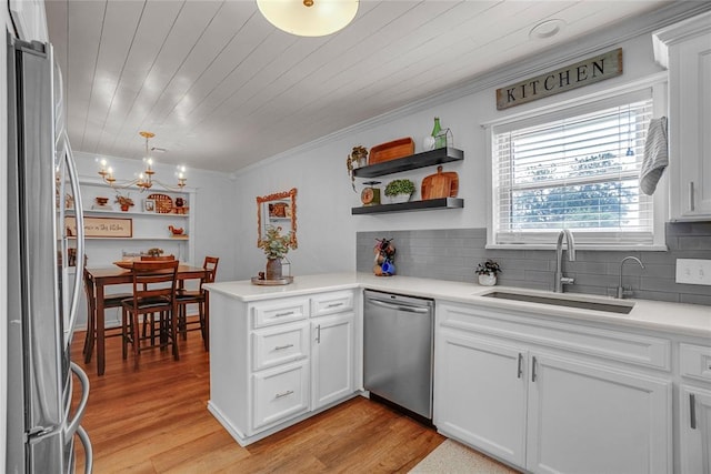 kitchen featuring sink, kitchen peninsula, appliances with stainless steel finishes, white cabinets, and light wood-type flooring