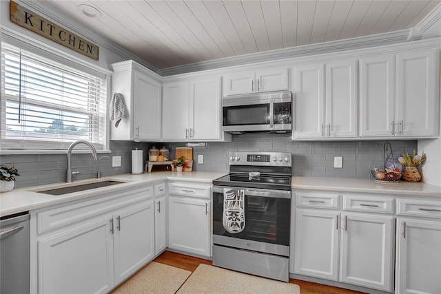 kitchen featuring white cabinets, sink, light wood-type flooring, ornamental molding, and appliances with stainless steel finishes