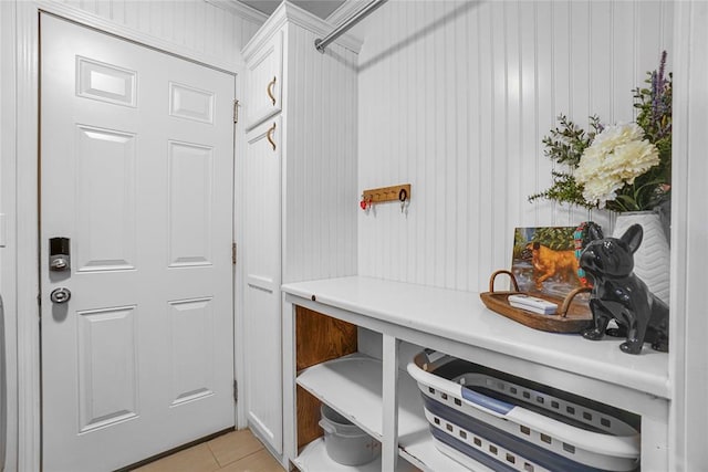 mudroom with light tile patterned floors and crown molding