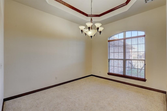 spare room featuring a notable chandelier, ornamental molding, light carpet, and a tray ceiling