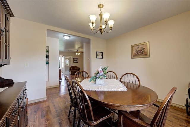 dining space with ceiling fan with notable chandelier and dark hardwood / wood-style flooring