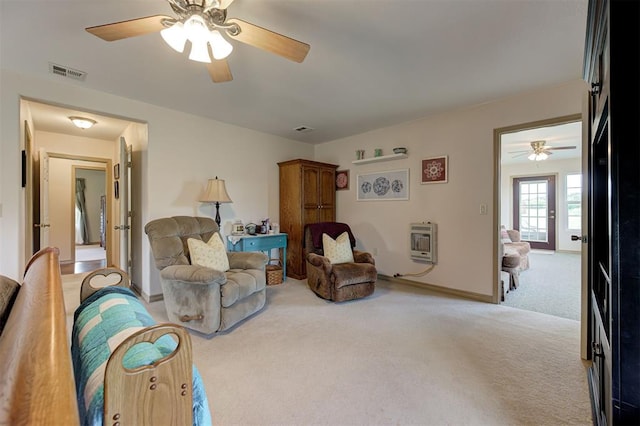 living area with ceiling fan, light carpet, and heating unit