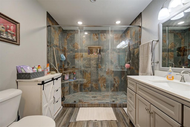 bathroom featuring vanity, toilet, and a shower with door