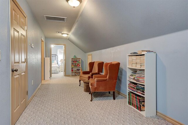 sitting room featuring light carpet and vaulted ceiling