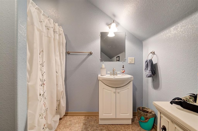 bathroom with a shower with shower curtain, vanity, a textured ceiling, and vaulted ceiling