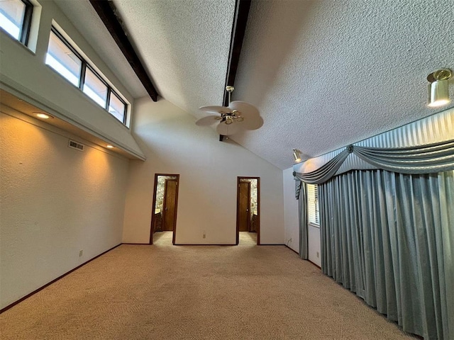 interior space with light carpet, beamed ceiling, and a textured ceiling