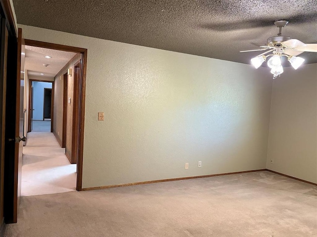 unfurnished room featuring a textured ceiling, ceiling fan, and light carpet