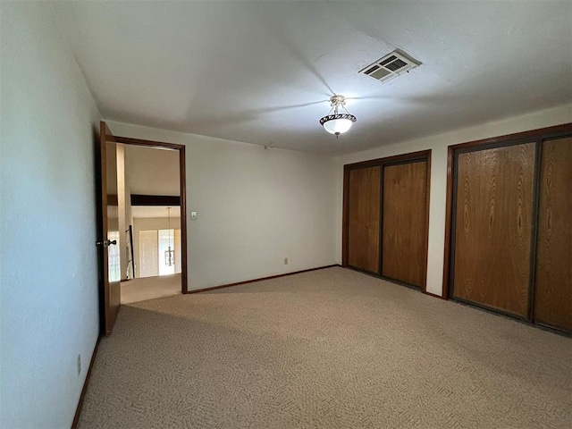 unfurnished bedroom with light colored carpet and multiple closets