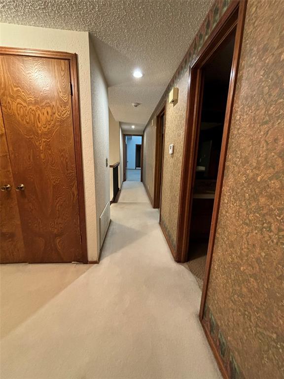 corridor featuring light carpet and a textured ceiling