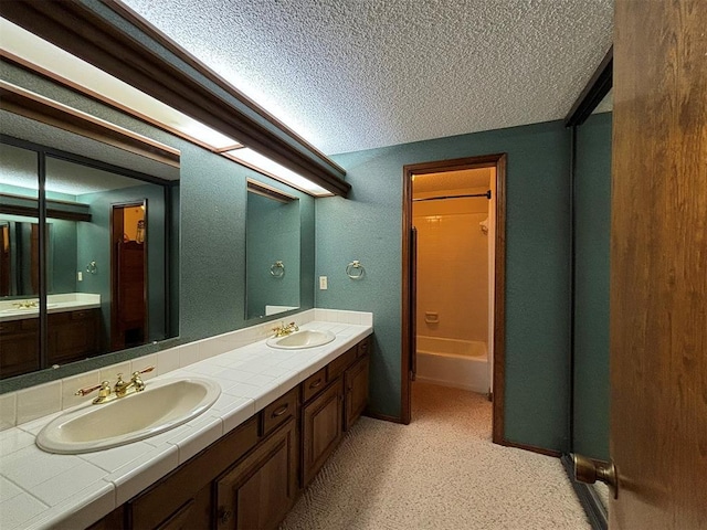 bathroom featuring vanity, a textured ceiling, and bathtub / shower combination