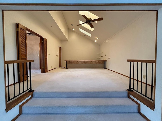 stairs with carpet flooring, ceiling fan, high vaulted ceiling, and a skylight