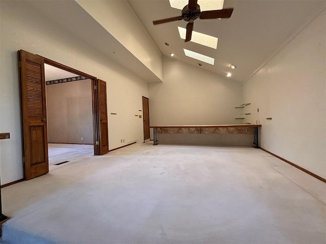 carpeted empty room with a skylight, high vaulted ceiling, and ceiling fan