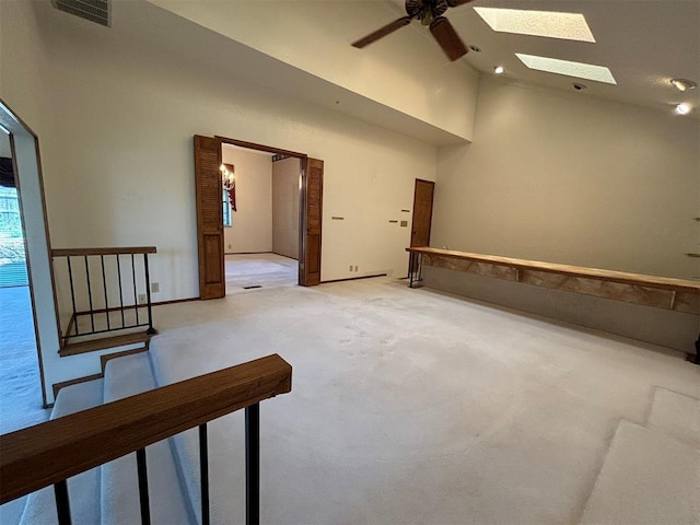 spare room with a skylight, high vaulted ceiling, and ceiling fan