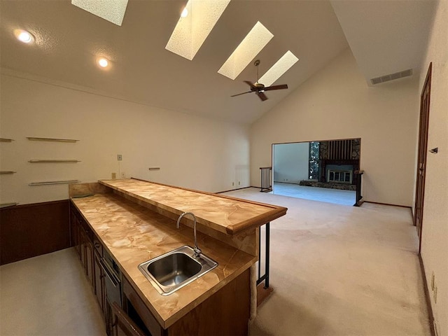 bar with wood counters, light carpet, high vaulted ceiling, sink, and a skylight