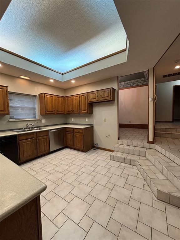 kitchen featuring dishwasher, light tile patterned floors, a textured ceiling, and sink