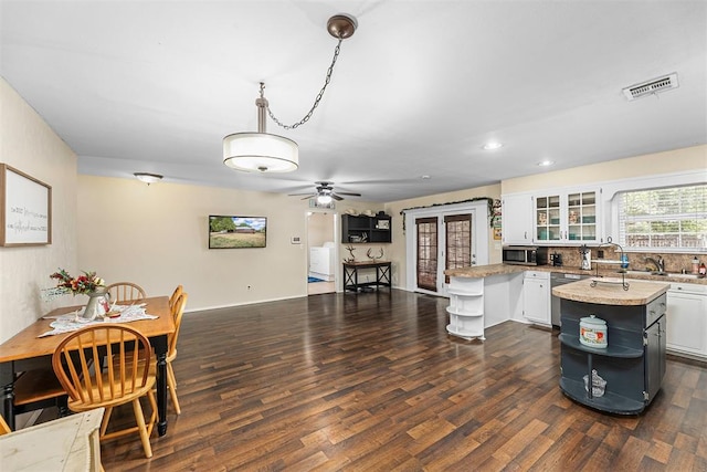 kitchen featuring a center island, white cabinets, dark hardwood / wood-style floors, decorative light fixtures, and light stone counters