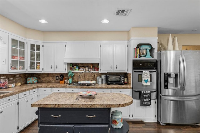 kitchen with a center island, white cabinets, dark wood-type flooring, and appliances with stainless steel finishes