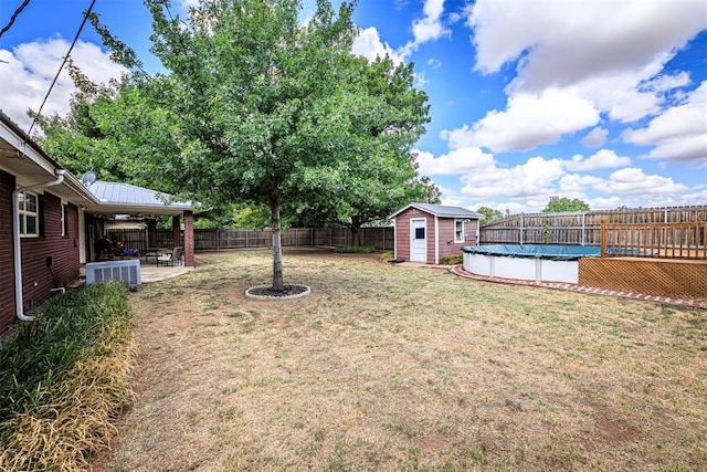 view of yard featuring a patio area, a covered pool, and a storage shed