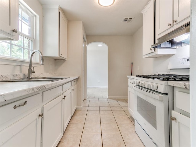 kitchen featuring white cabinets, light tile patterned floors, gas range gas stove, and sink