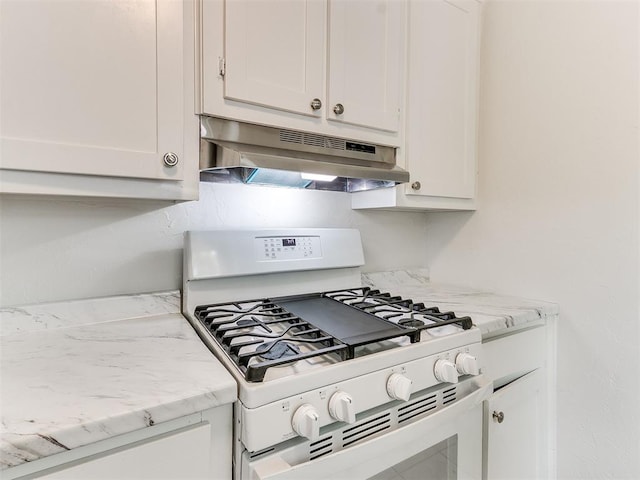 kitchen featuring white cabinets, white gas stove, and light stone countertops