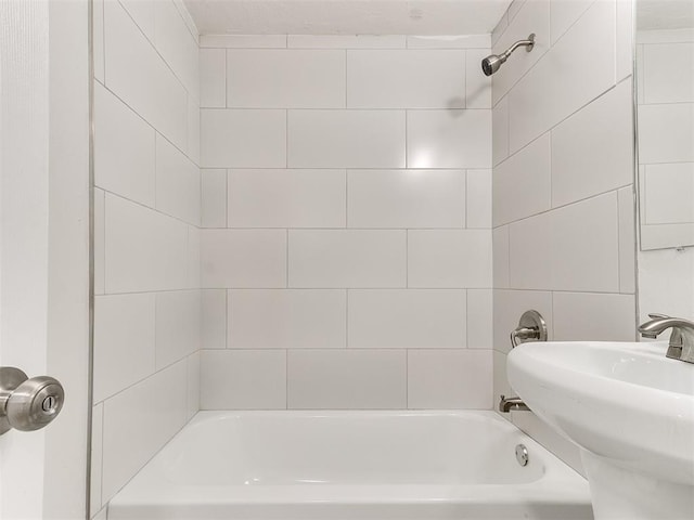 bathroom featuring tiled shower / bath combo and sink