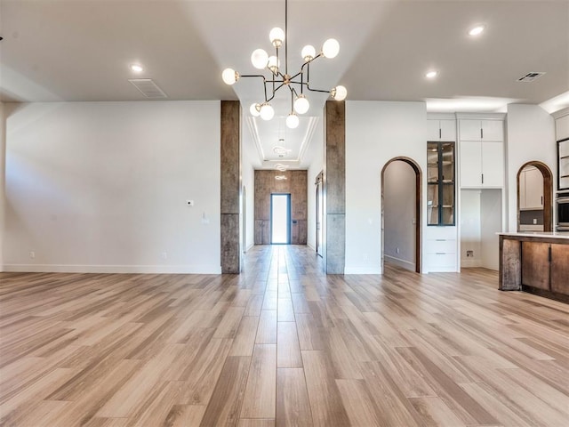 kitchen featuring stainless steel oven, decorative light fixtures, light hardwood / wood-style flooring, a notable chandelier, and white cabinetry