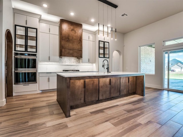 kitchen featuring a center island with sink, hanging light fixtures, and light hardwood / wood-style flooring