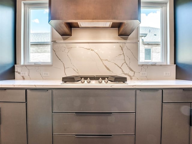 kitchen with decorative backsplash, custom range hood, gray cabinets, and white gas stovetop