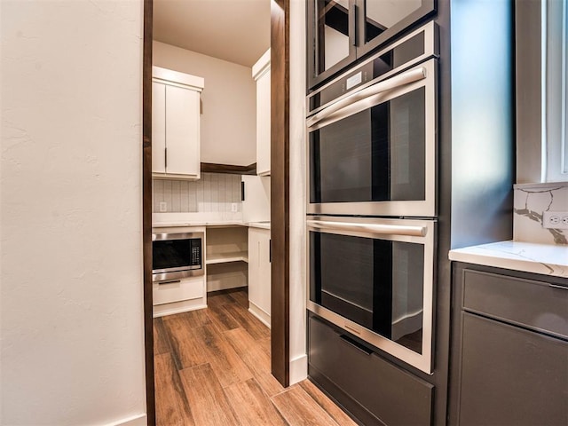 kitchen featuring decorative backsplash, white cabinetry, light hardwood / wood-style flooring, and stainless steel appliances