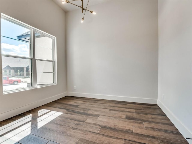 unfurnished room featuring a wealth of natural light, hardwood / wood-style floors, and a chandelier