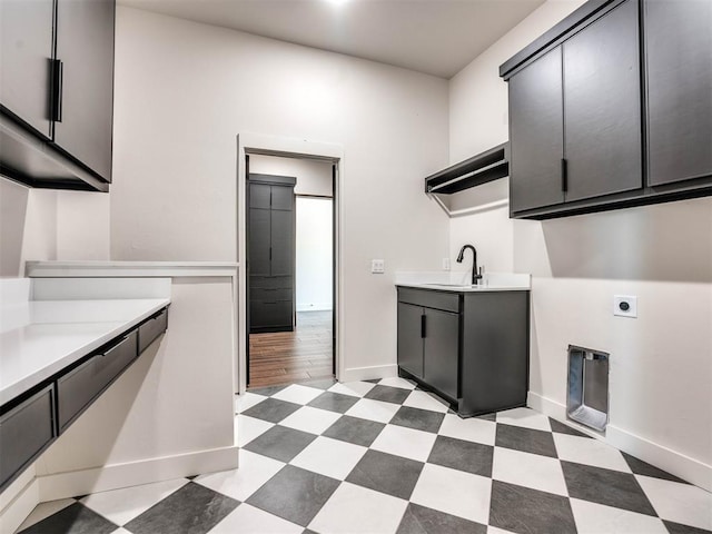 clothes washing area with electric dryer hookup, cabinets, sink, and light hardwood / wood-style flooring