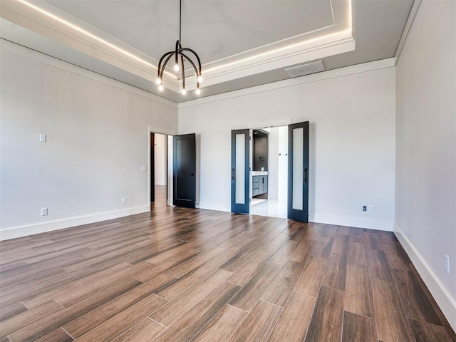 spare room with a raised ceiling, wood-type flooring, and a high ceiling