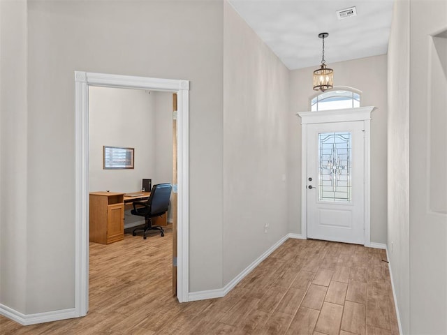 foyer with light wood-type flooring and an inviting chandelier