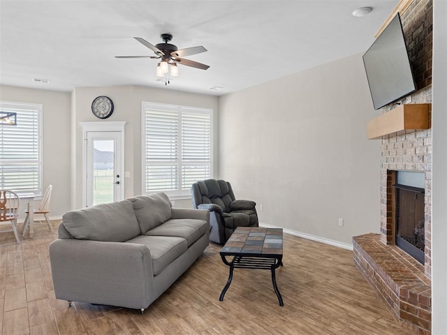 living room with light hardwood / wood-style floors, a brick fireplace, plenty of natural light, and ceiling fan