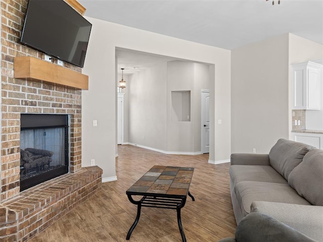 living room with a fireplace, an inviting chandelier, and light hardwood / wood-style flooring