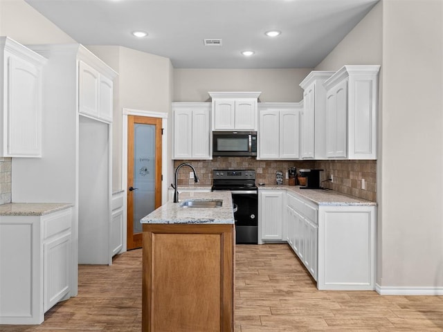 kitchen with sink, light stone counters, black / electric stove, light hardwood / wood-style floors, and white cabinets