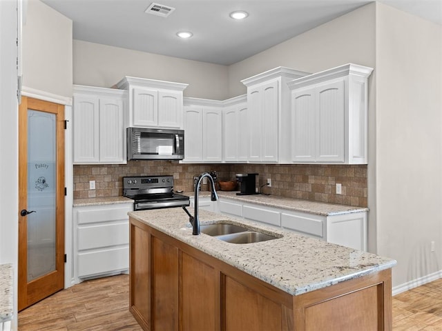 kitchen with appliances with stainless steel finishes, light hardwood / wood-style flooring, and white cabinetry