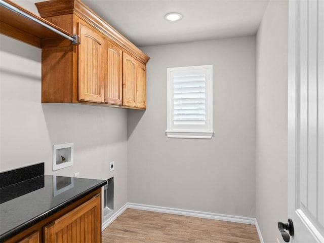 washroom featuring electric dryer hookup, hookup for a washing machine, light hardwood / wood-style flooring, and cabinets